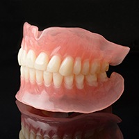 Set of dentures on a reflective black background