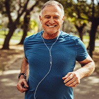 Senior man smiling while jogging outside
