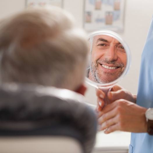 Man looking in mirror after smile makeover