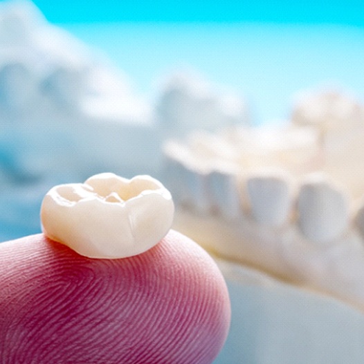 Closeup of dental crown in Pensacola on finger