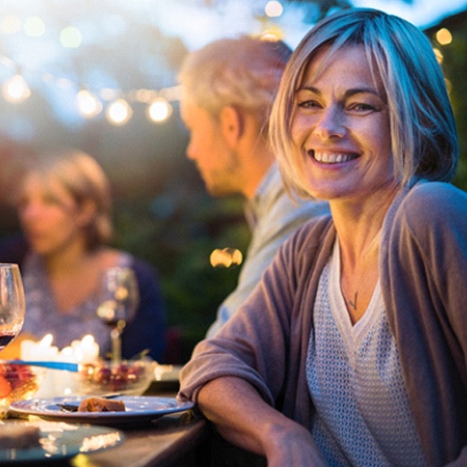 Woman smiling with dental crown in Pensacola at dinner party
