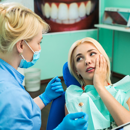 A young woman complaining to her dentist about a toothache