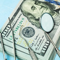 stack of money and dental tools