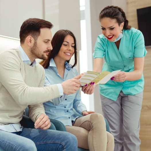 Man and woman discussing the cost of treating dental emergencies with team member