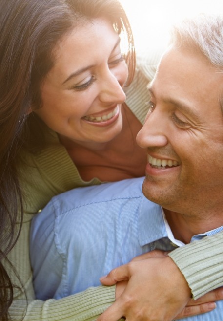 Man and woman smiling after tooth replacement with dental implants