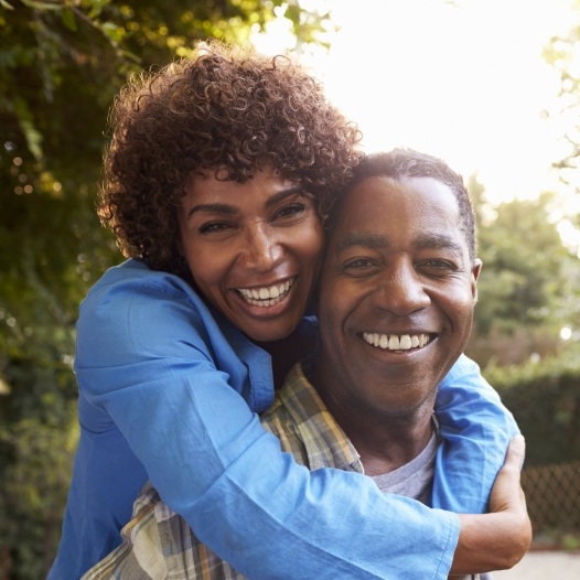 Man and woman sharting healthy smiles after dental implant tooth replacement