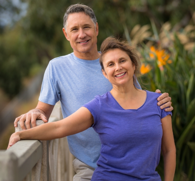 Man and woman in blue shirts smiling outdoors