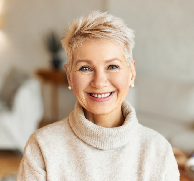 Senior woman smiling and wearing white sweater