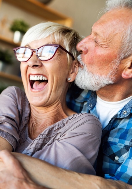 Man and woman laughing together after replacing missing teeth