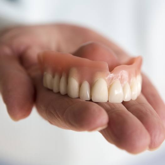 Hand holding a full denture