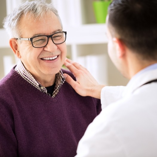 Man smiling at dentist after dental implant tooth replacement