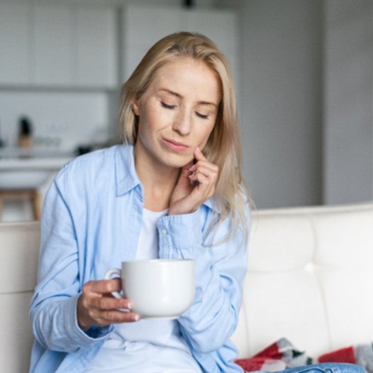 Woman sitting on couch with tooth pain