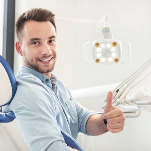 man in dental chair giving thumbs up 