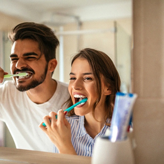 couple brushing teeth together in bathroom