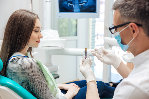 Male dentist showing his female patient a dental implant 