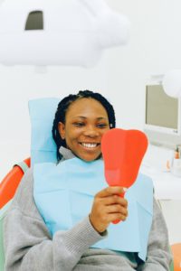 Smiling female dental patient looking in mirror
