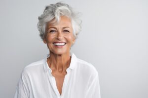 Woman with white and grey hair in a white shirt smiling
