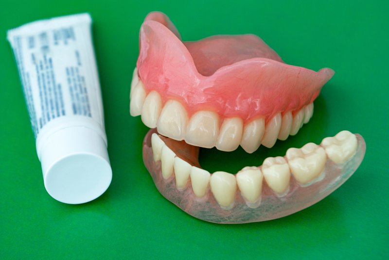 a pair of dentures next to a tube of denture adhesive
