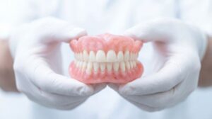 Gloved hands holding full set of dentures