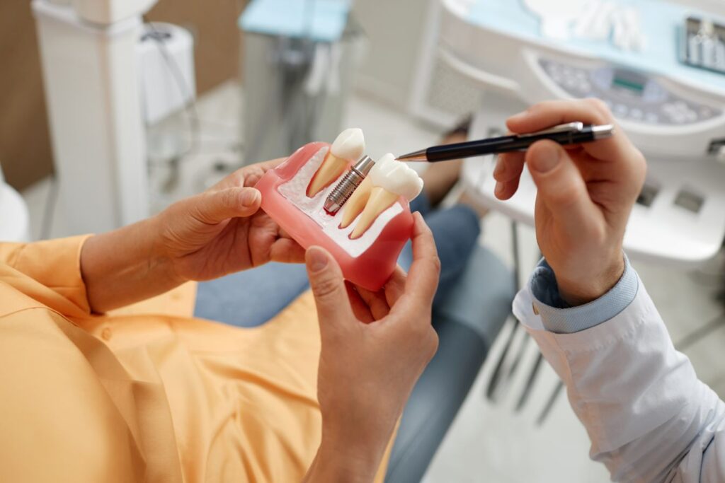A dentist showing a patient a model of a dental implant